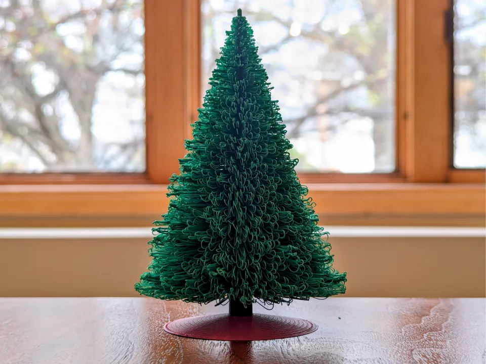 Green spiral Christmas tree on a red stand in a window