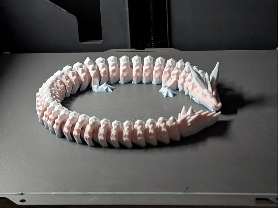 Pink and white articulated spike dragon curled in a ring