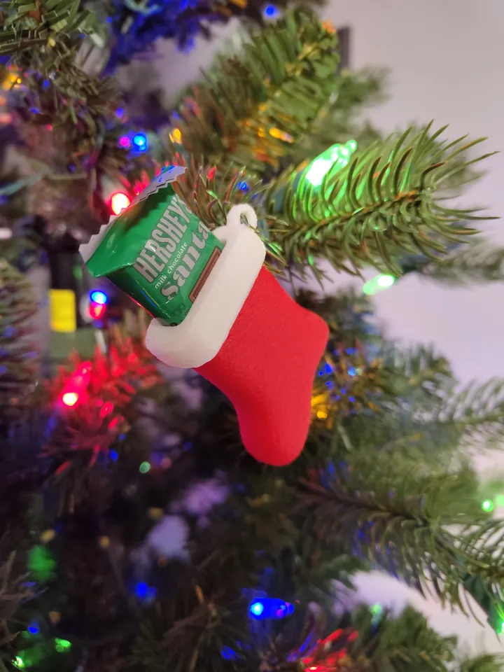 Small red and white stocking ornament hanging on a Christmas tree