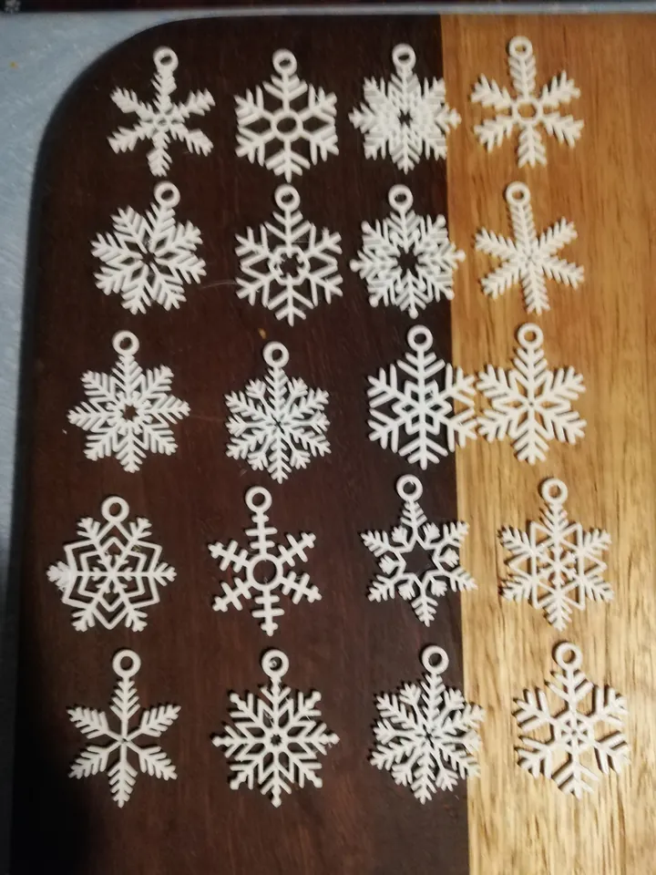 Twenty white snowflake ornaments laid out on a wood table